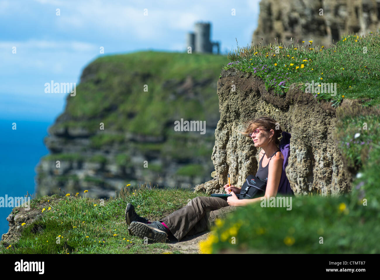 Una giovane donna gode della vista delle scogliere di Moher, County Clare, Irlanda. Foto Stock