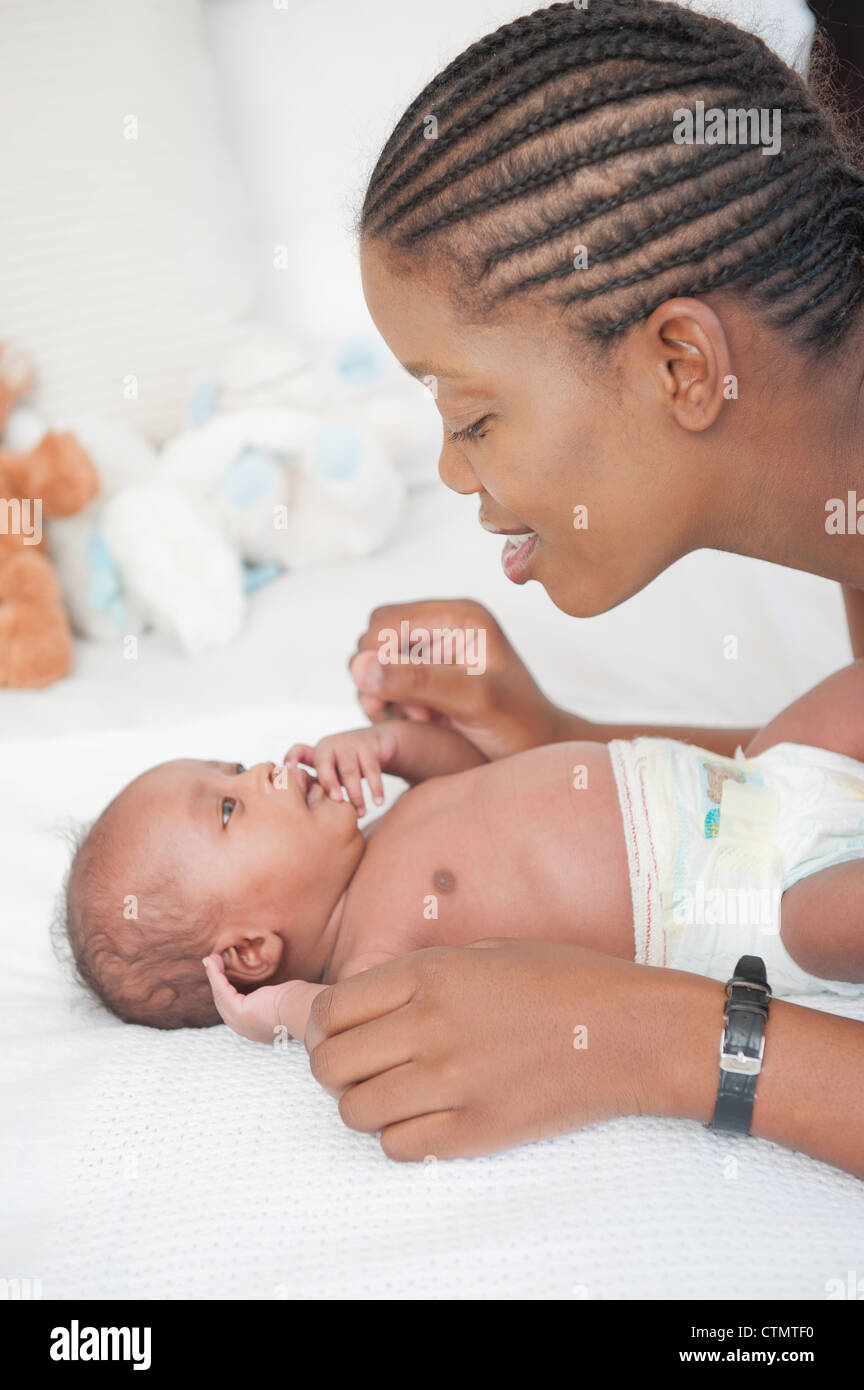 La madre parla al suo neonato sdraiato sul letto a Johannesburg, Sud Africa Foto Stock