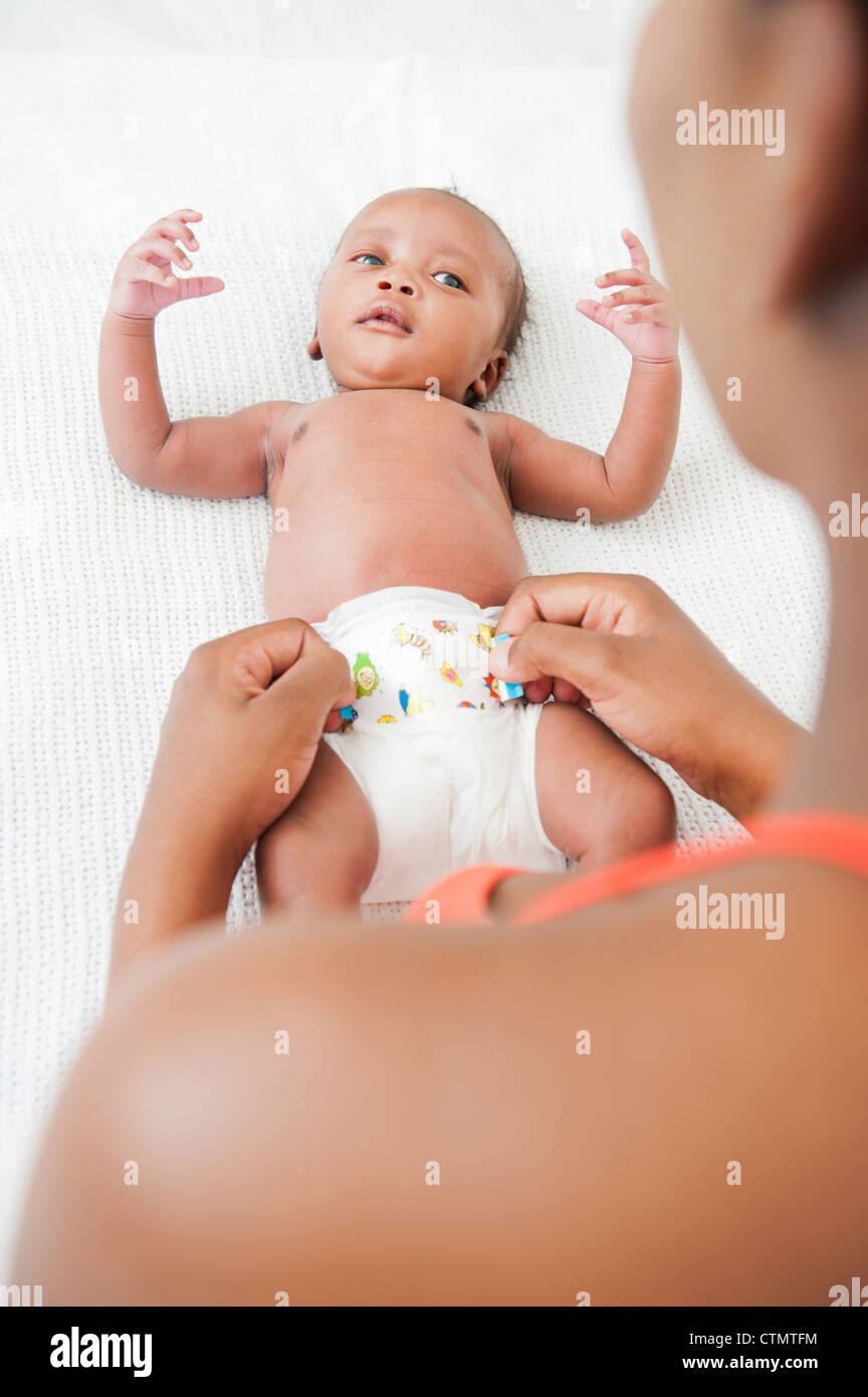 Oltre la spalla di madre cambiando il pannolino del suo neonato) giacente sul letto in Johannesburg, Sud Africa Foto Stock