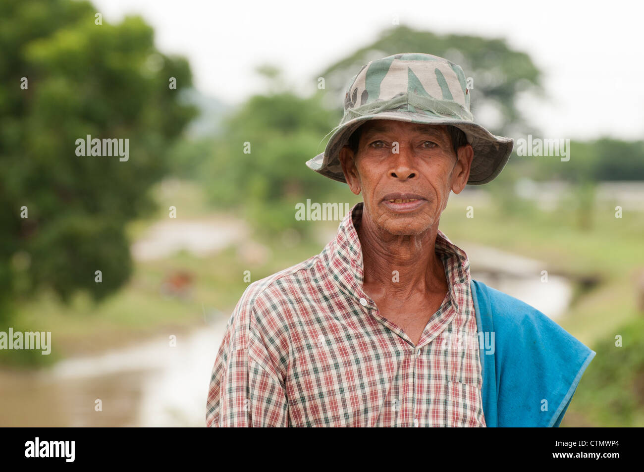 Una immagine di un vecchio maschio tailandese abitante che indossa una camicia a quadri e un esercito di hat. Presa all'aperto dal canale locale phetburi thailandia Foto Stock