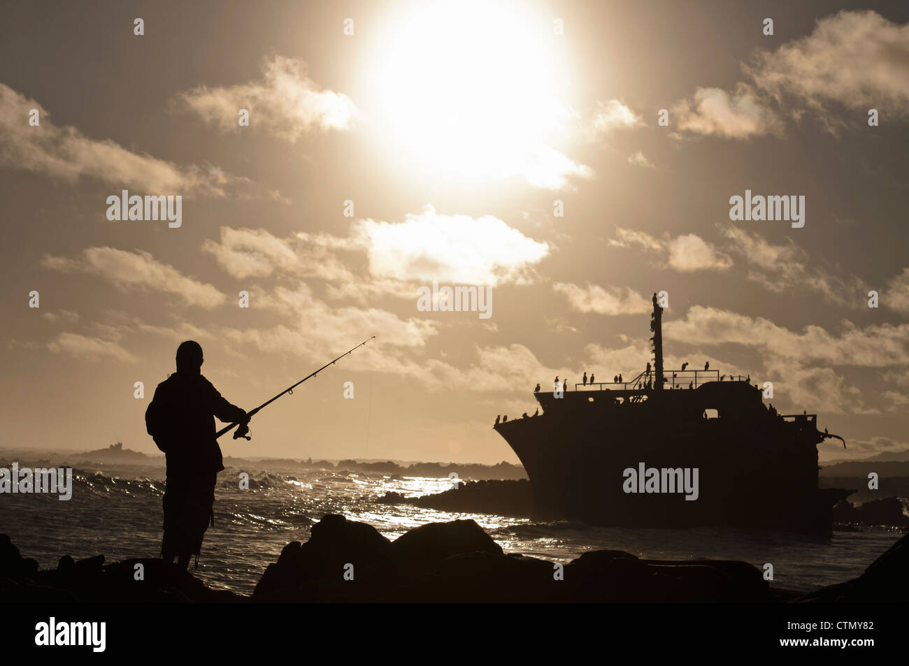 Pescatore e il relitto della nave al tramonto, Cape Agulhas, Western Cape, Sud Africa Foto Stock