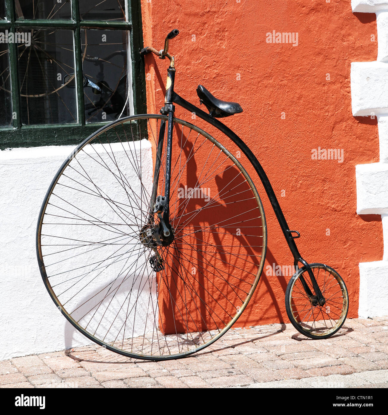 Un antico bicicletta appoggiata contro la parete in stucco di un edificio in Bermuda. Foto Stock