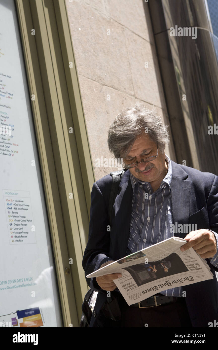 L'uomo legge la notizia nella NY Times lungo 42nd St. dalla Grand Central Station, NYC Foto Stock