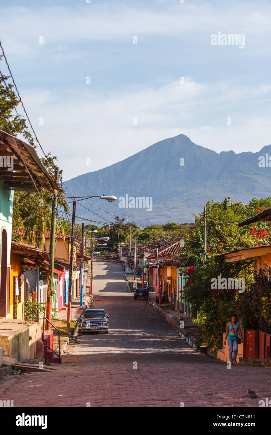 Case colorate fiancheggiano una strada acciottolata di Granada con montagne sullo sfondo Foto Stock