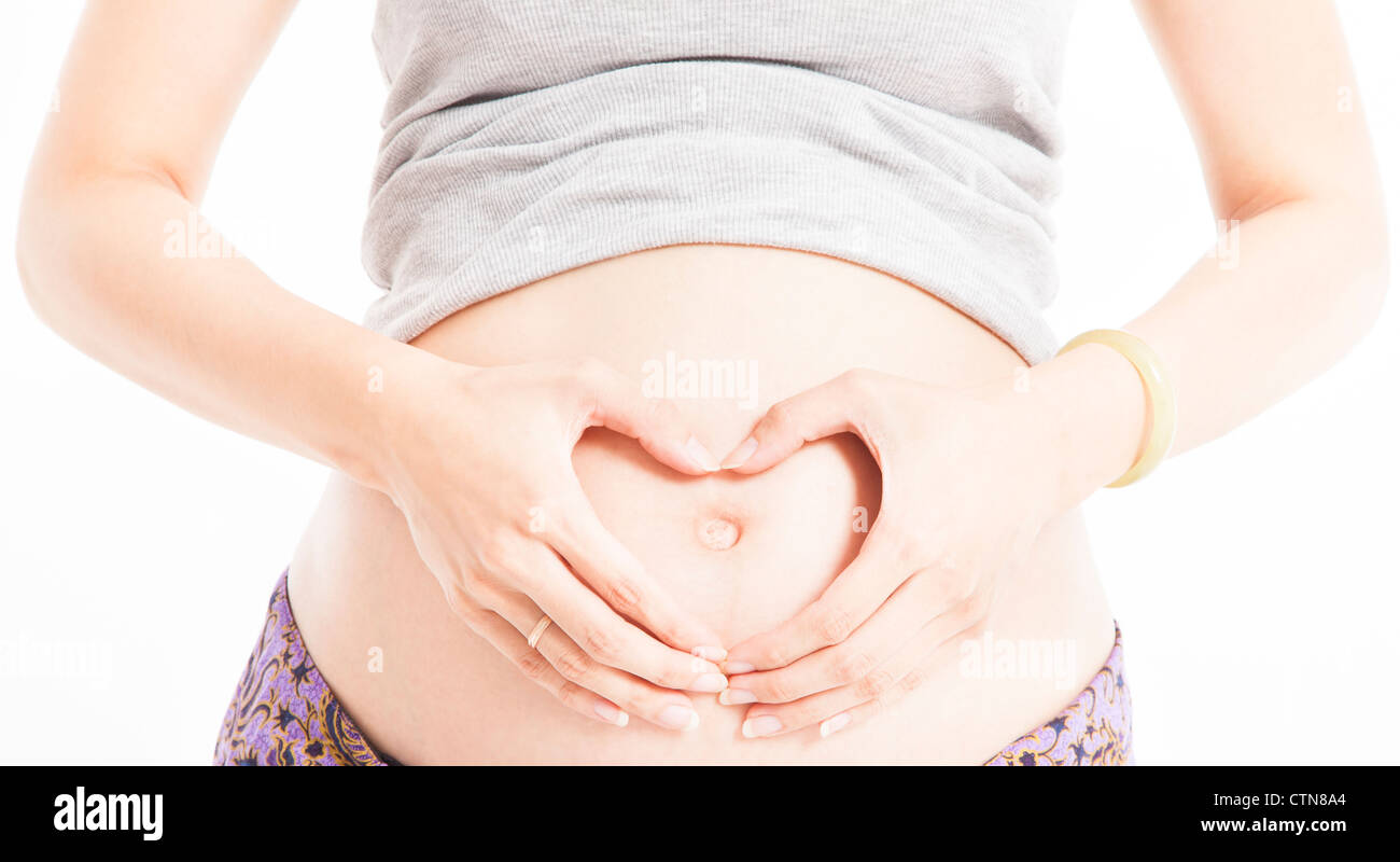 Pancia in gravidanza con mom messa a forma di cuore con le mani Foto Stock
