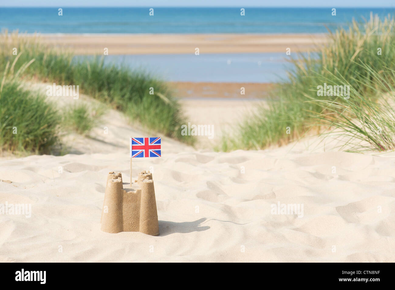 Union Jack flag in un castello di sabbia sulle dune di sabbia. Pozzetti accanto al mare. Norfolk, Inghilterra Foto Stock