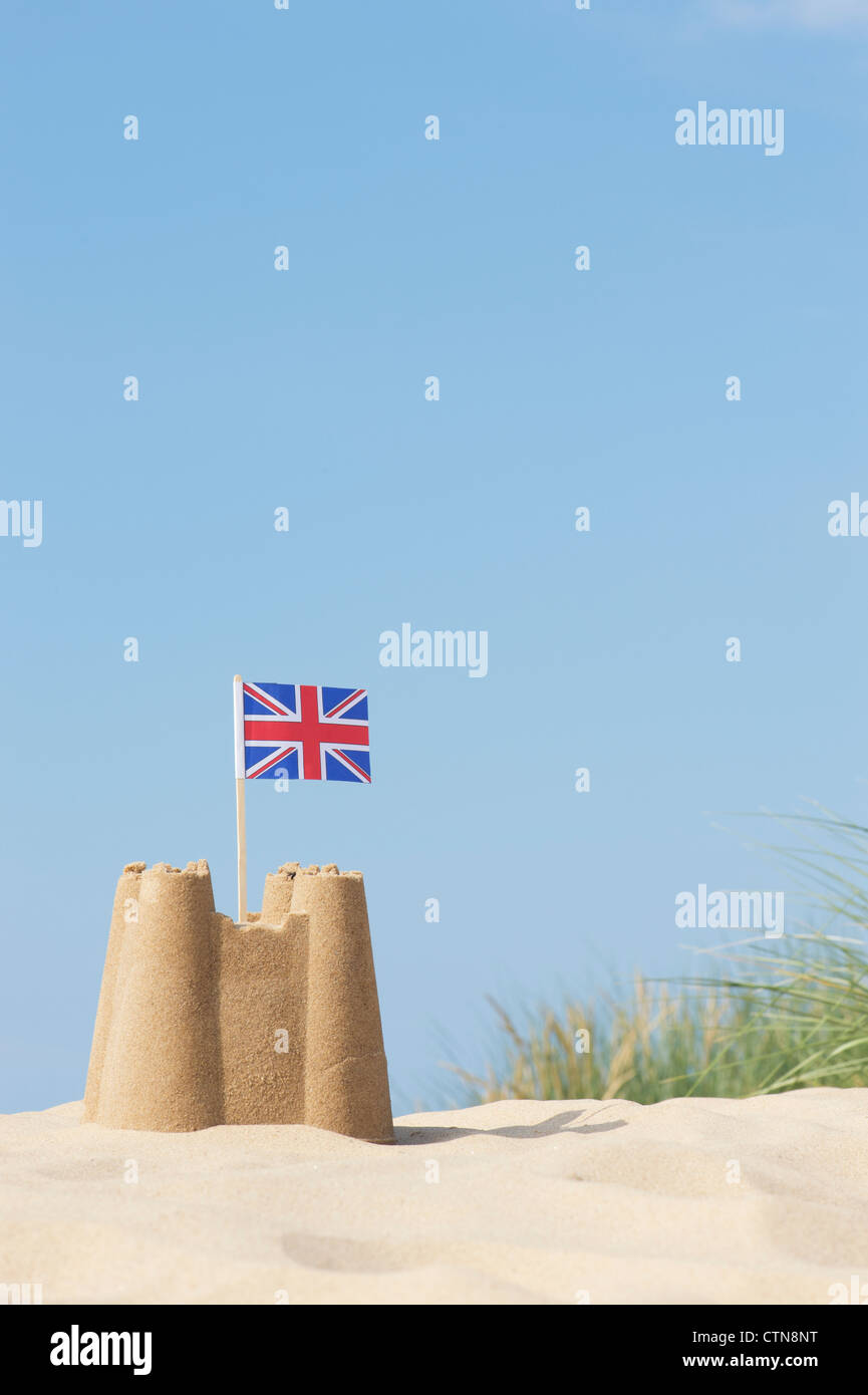 Union Jack flag in un castello di sabbia sulle dune di sabbia. Pozzetti accanto al mare. Norfolk, Inghilterra Foto Stock