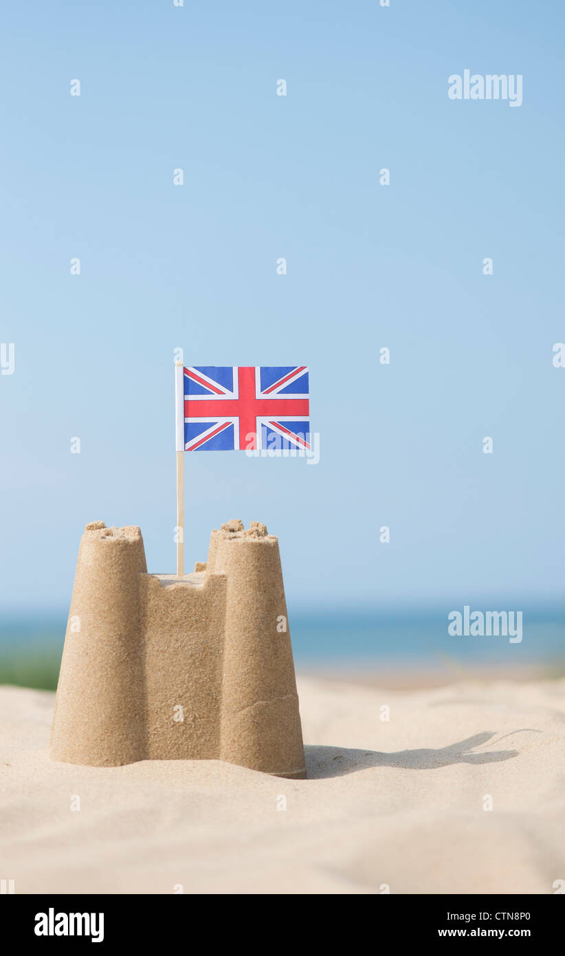 Union Jack flag in un castello di sabbia sulla spiaggia. Pozzetti accanto al mare. Norfolk, Inghilterra Foto Stock