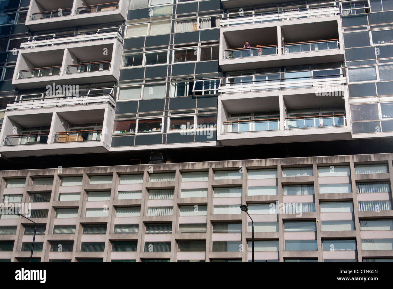 Anni sessanta calcestruzzo torre residenziale di blocco con due uomini guardando fuori da uno dei balconi degli appartamenti Londra Inghilterra REGNO UNITO Foto Stock