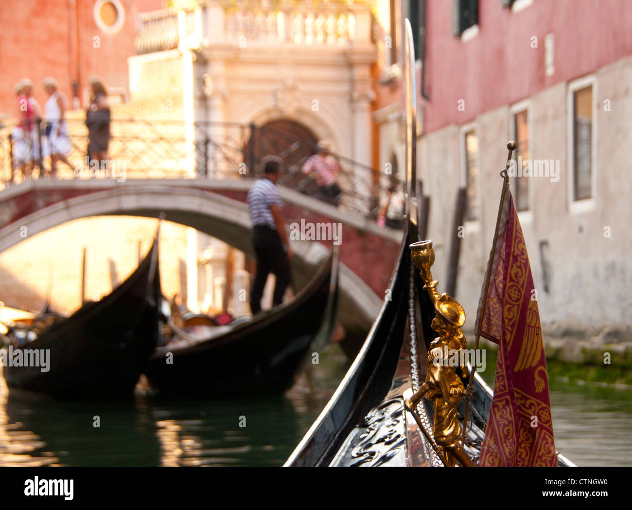 Vista da a bordo di una gondola lungo il canale tipico con la prua della barca, gondoliere, le gondole e le persone sul ponte Venezia Veneto Italia Foto Stock