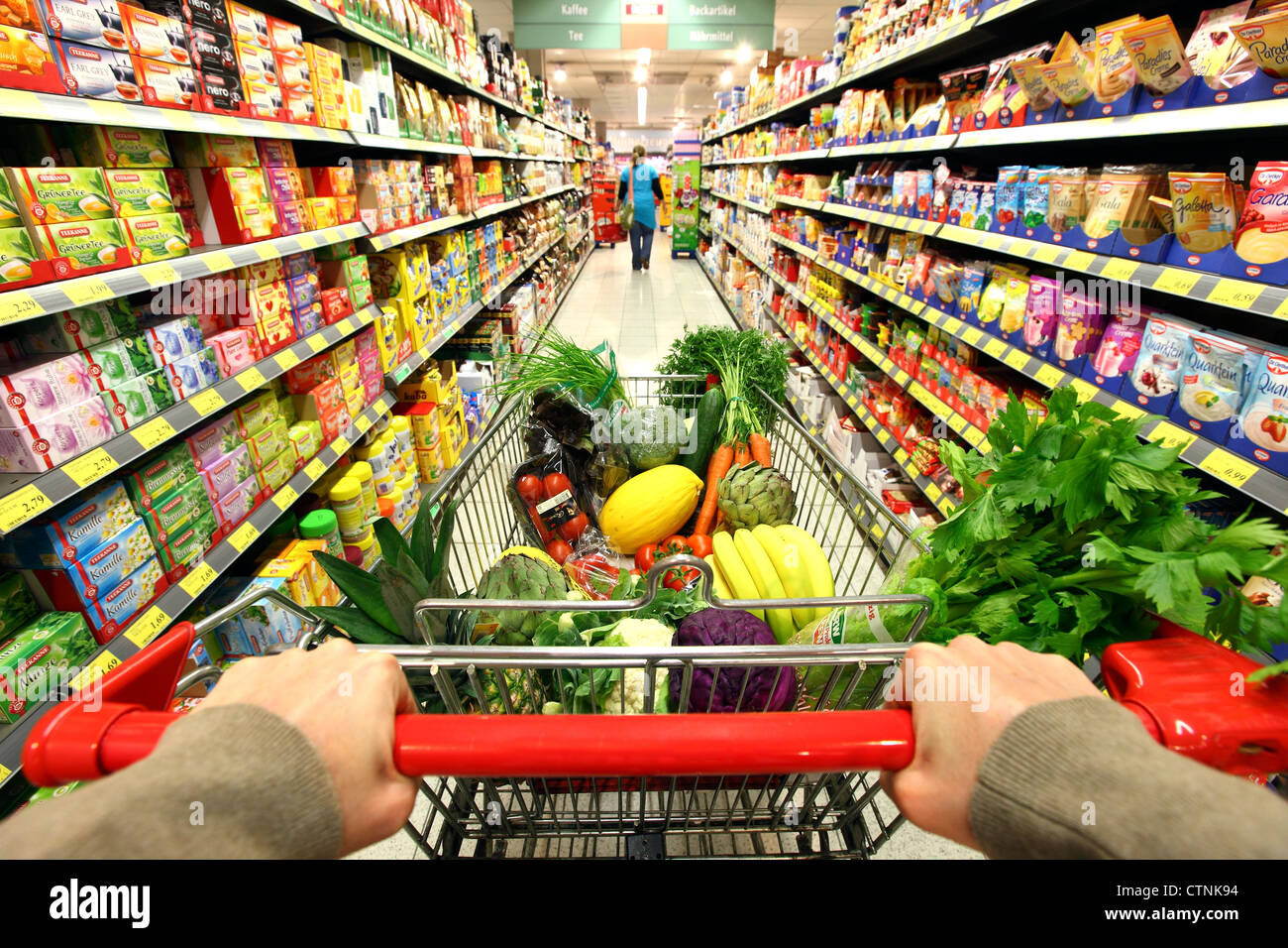 Food Hall, pieno carrello è spinto attraverso un corridoio con diversi prodotti alimentari. Grande supermercato self service. Foto Stock