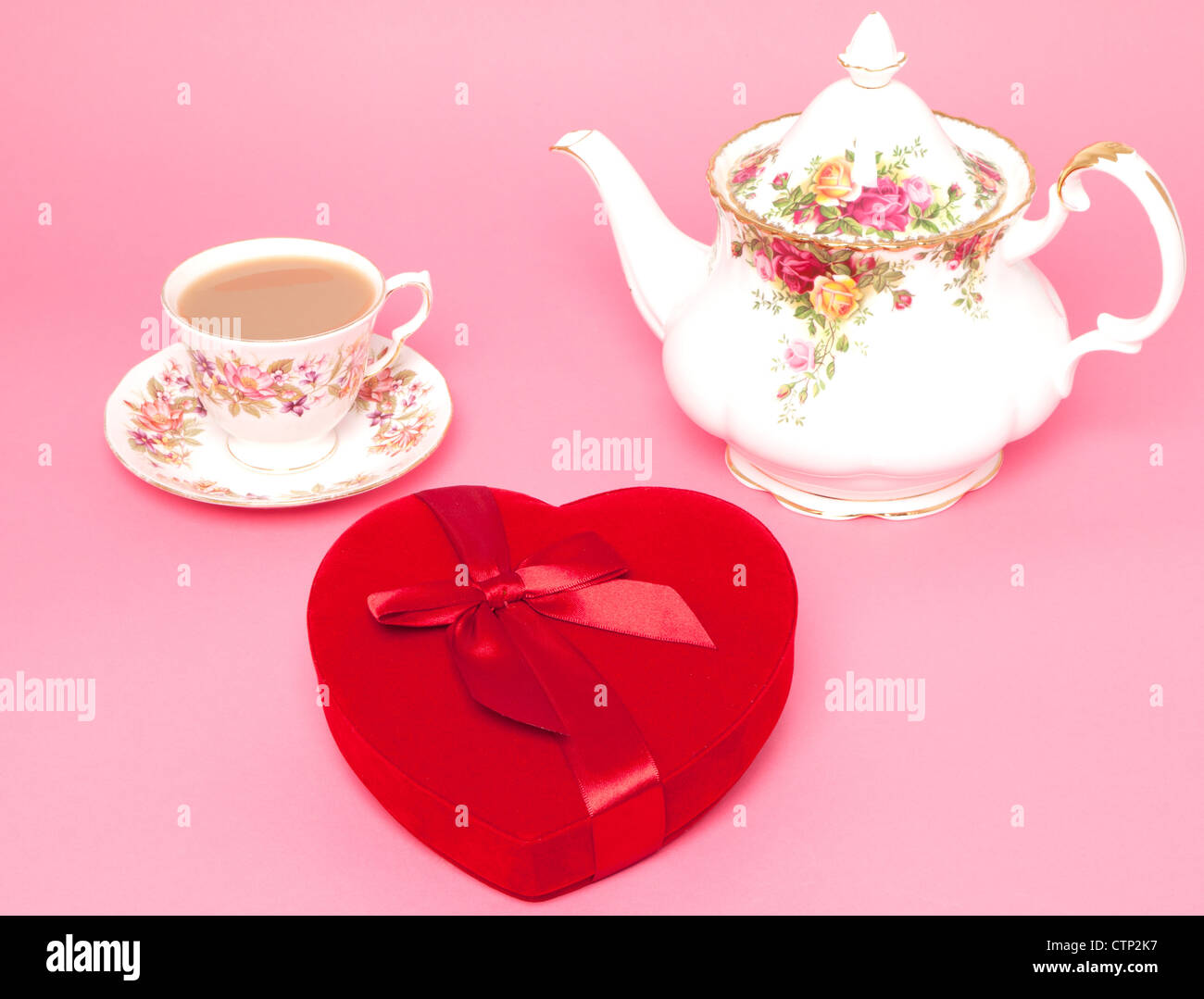 Un osso di cina teiera e tazza e piattino con un rosso a forma di cuore ad una scatola di cioccolatini - Studio shot Foto Stock