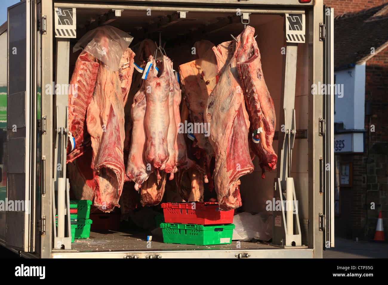 Carne appesi da un macellaio camion sotto il sole in un British High Street Foto Stock