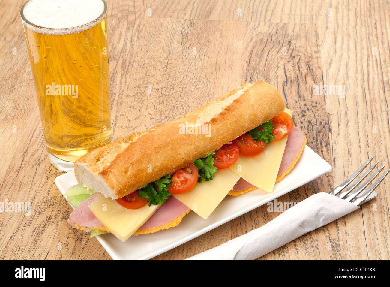 Un pranzo in un pub tradizionale di un prosciutto, formaggio e insalata servita a sandwich in una fetta di pane francese del baguette, accompagnati da una birra. Foto Stock