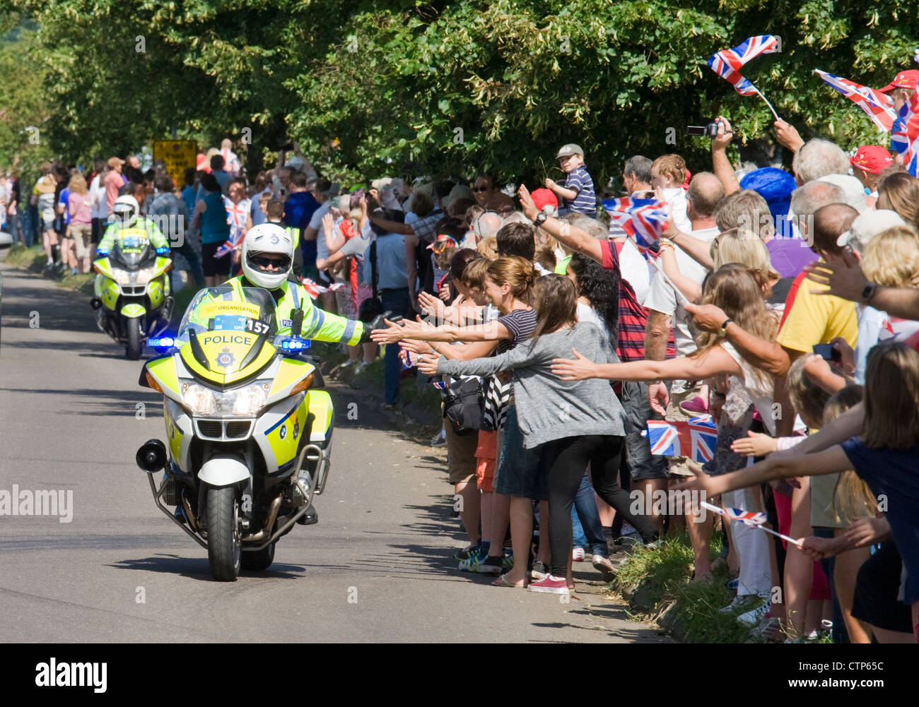 Il messaggio di saluto della folla la polizia davanti agli uomini del ciclo gara su strada, Londra 2012 Giochi Olimpici. Ripley, Surrey. Foto Stock