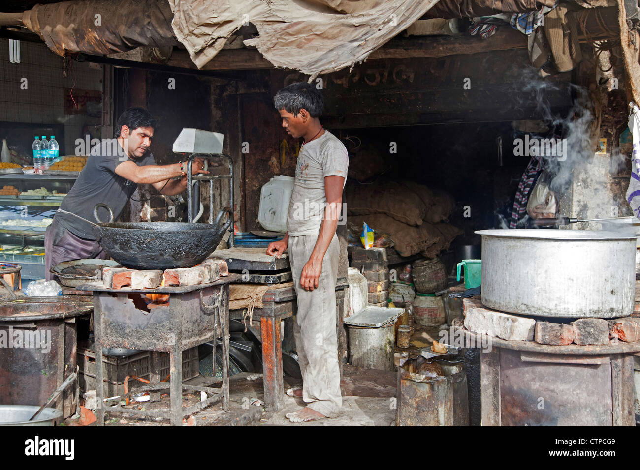 Gli uomini di cottura degli alimenti in presenza di sporco insalubrità cucina primitiva in Mathura, Uttar Pradesh, India Foto Stock