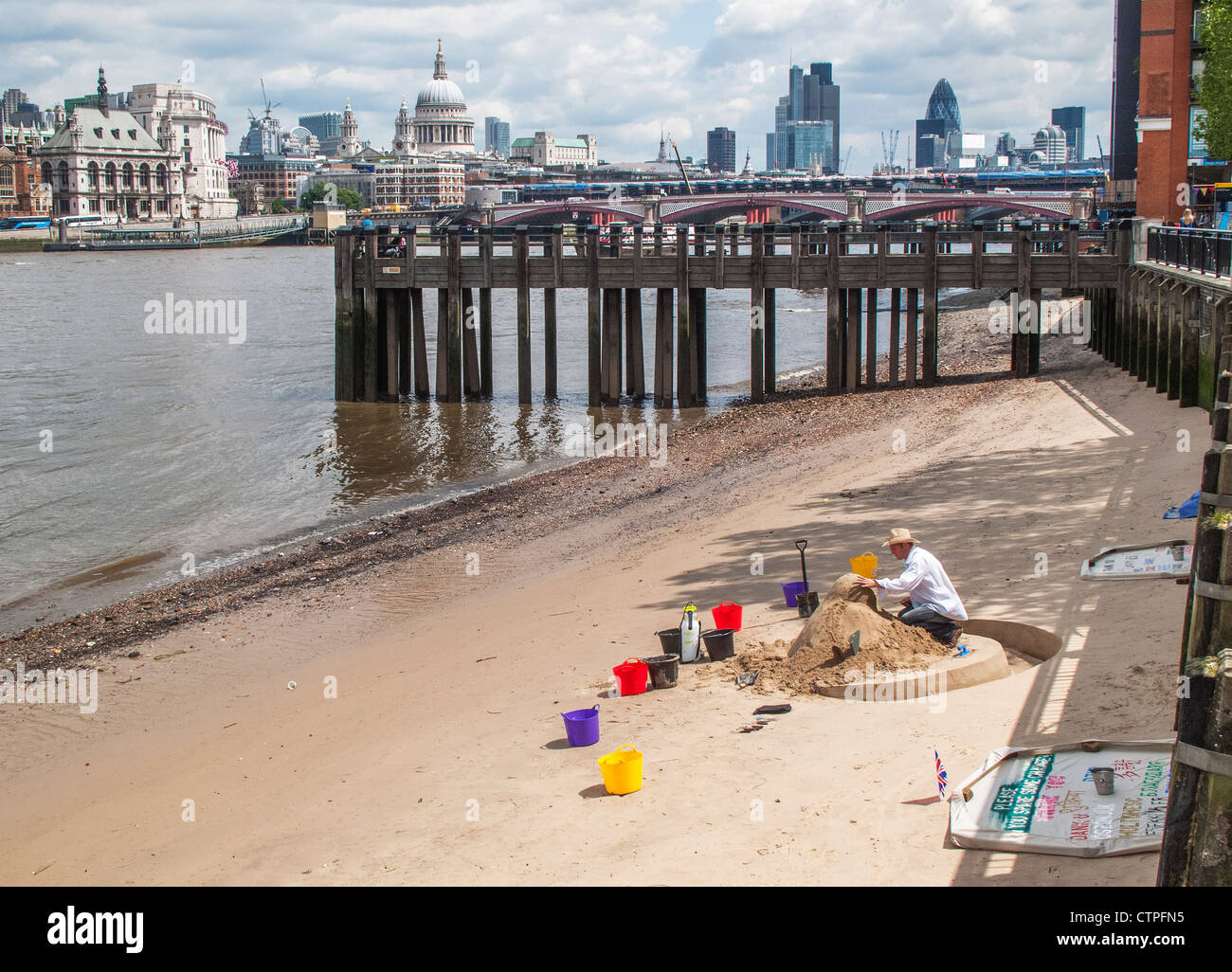 L'uomo costruire le sculture di sabbia per sul terrapieno a sud del fiume Tamigi, raccolta di suggerimenti, con lo skyline di Londra in background Foto Stock