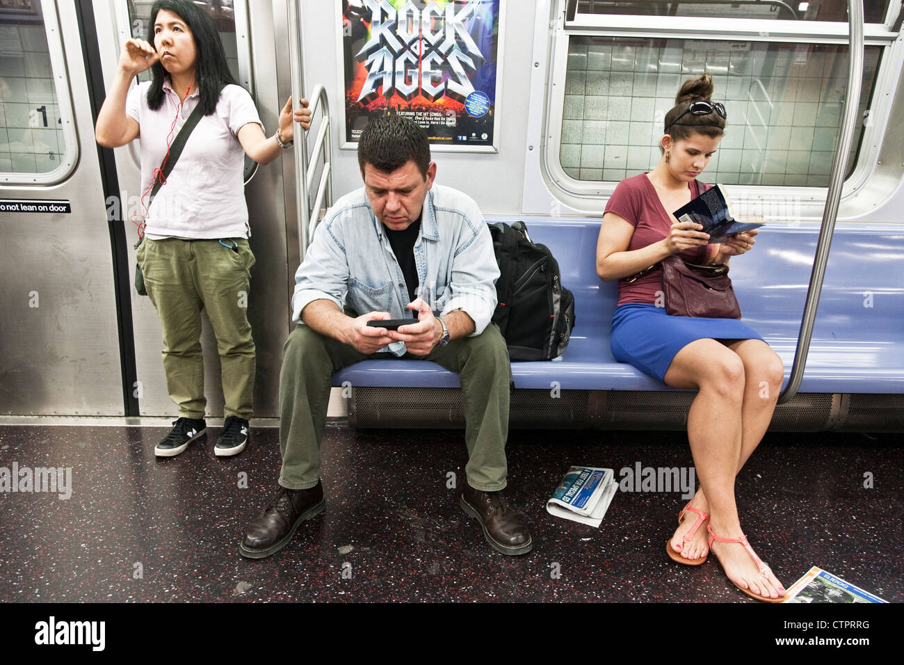 3 self assorbito New York alla metropolitana passeggeri, un uomo & 2 giovani donne, ciascuno assorbito in un mondo privato la lettura di messaggi di testo a sognare Foto Stock