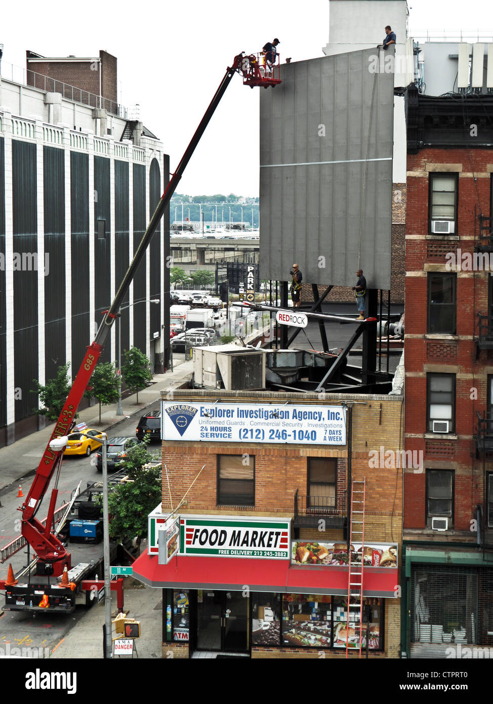 Cherry picker assiste operai ironworkers set cavi al bottino segno pubblicità su intelaiatura metallica ricoperta con lastre di acciaio Foto Stock