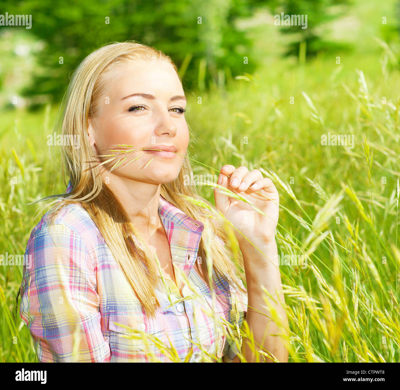 Carina ragazza bionda sul campo di grano, donna seduta su erba verde, femmina rilassante all'aperto, felice Pretty girl teen tenendo la segala Foto Stock