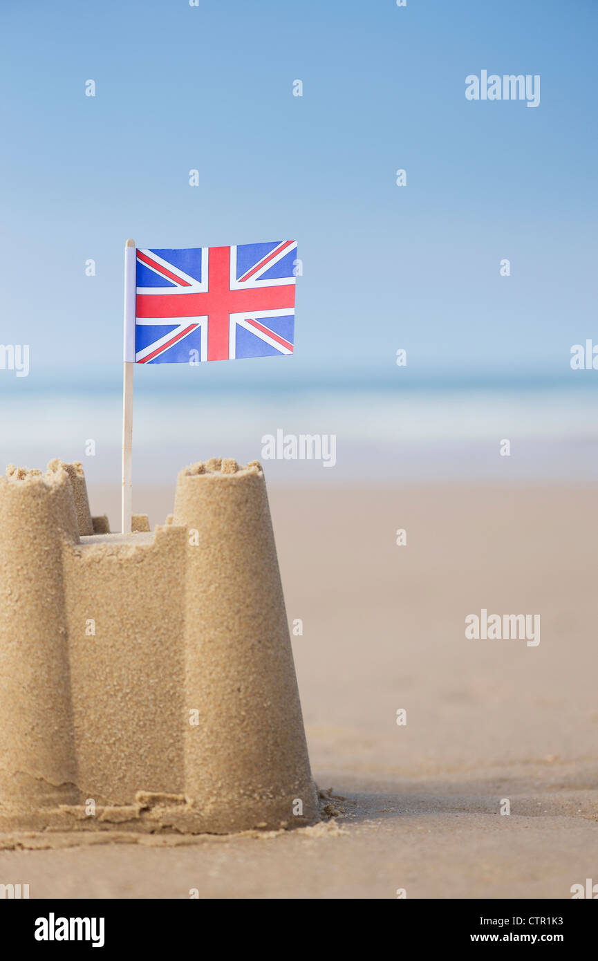 Union Jack flag in un castello di sabbia sulla spiaggia. Pozzetti accanto al mare. Norfolk, Inghilterra Foto Stock