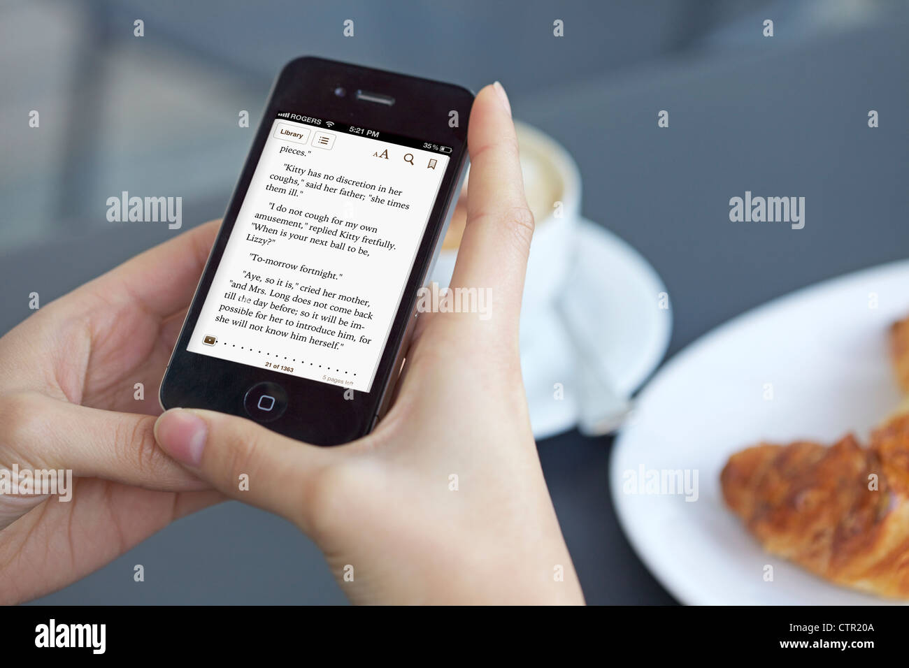 Vista ravvicinata della lettura femminile dal suo ibook app utilizzando un iphone 4s Foto Stock