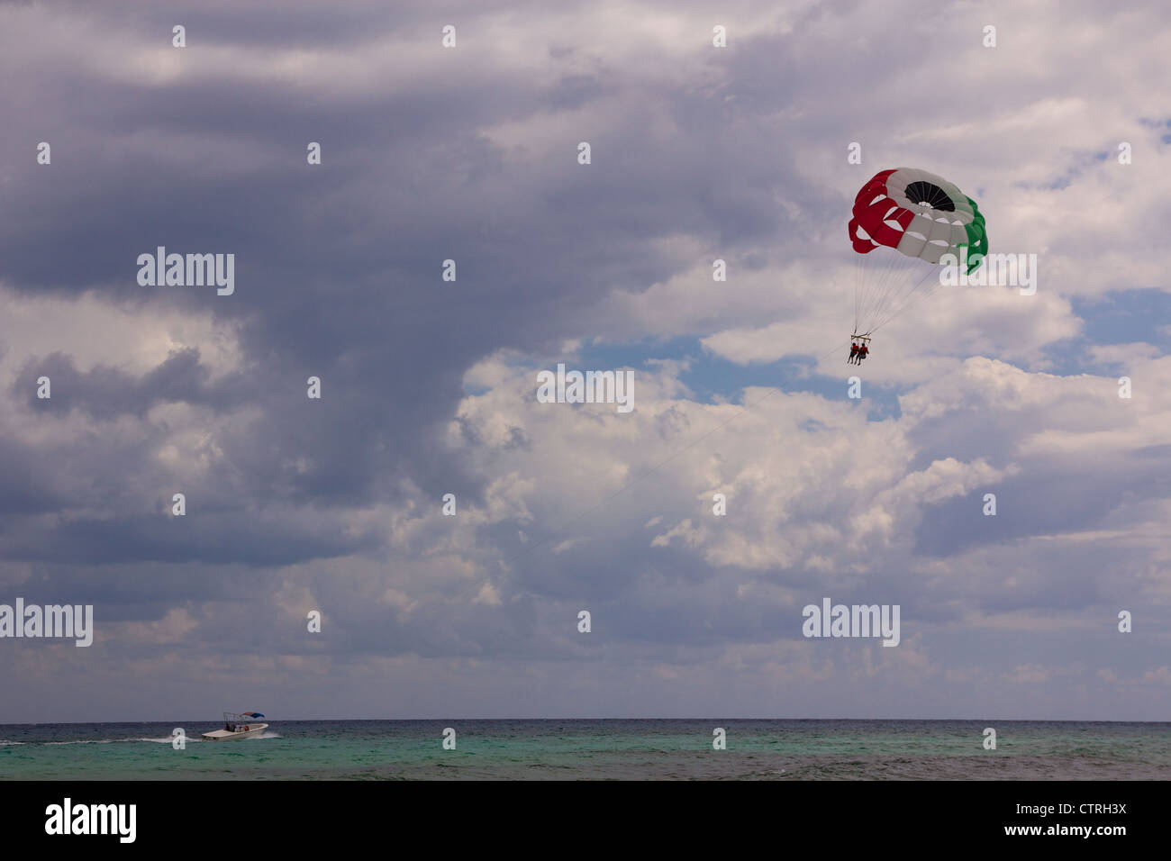 Scivolo di parapendio con i colori della bandiera messicana trainato da una barca a motore spento la spiaggia di Playa del Carmen, Messico. Foto Stock