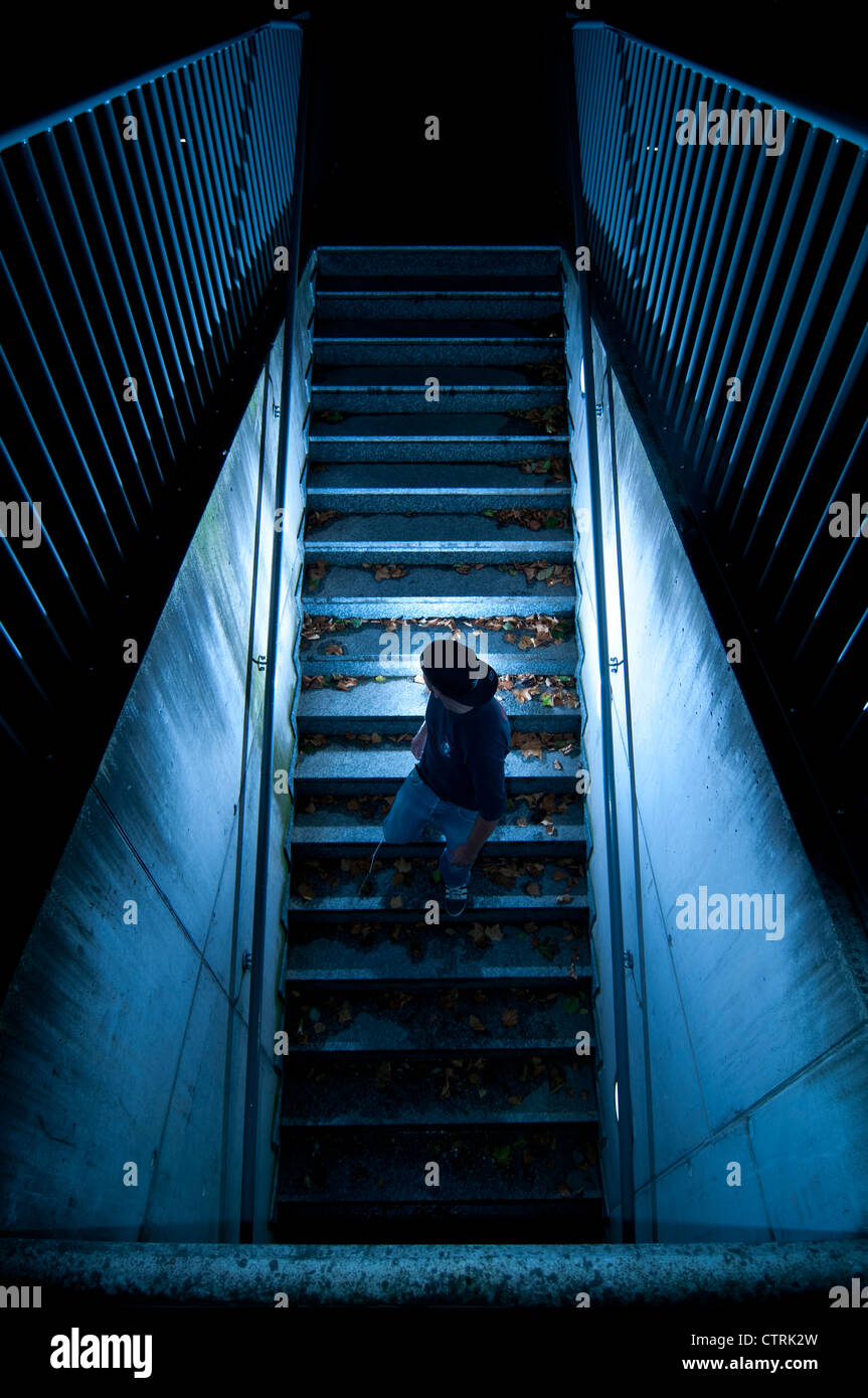 Giovane uomo che cammina giù per una scala buia Foto Stock