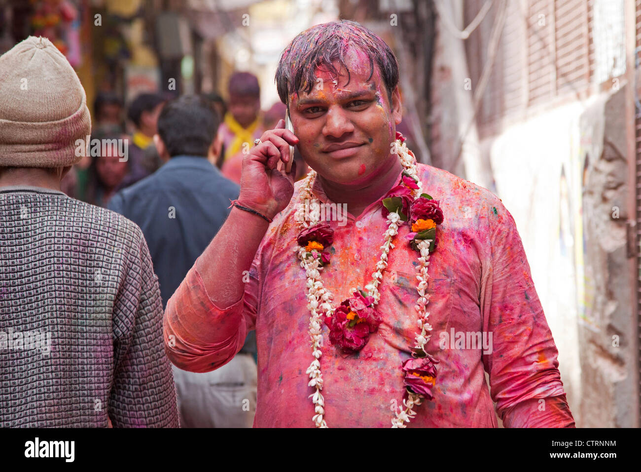 L'uomo tinto in rosso con cellulare celebra la Holi festival in Vrindavan, Uttar Pradesh, India Foto Stock