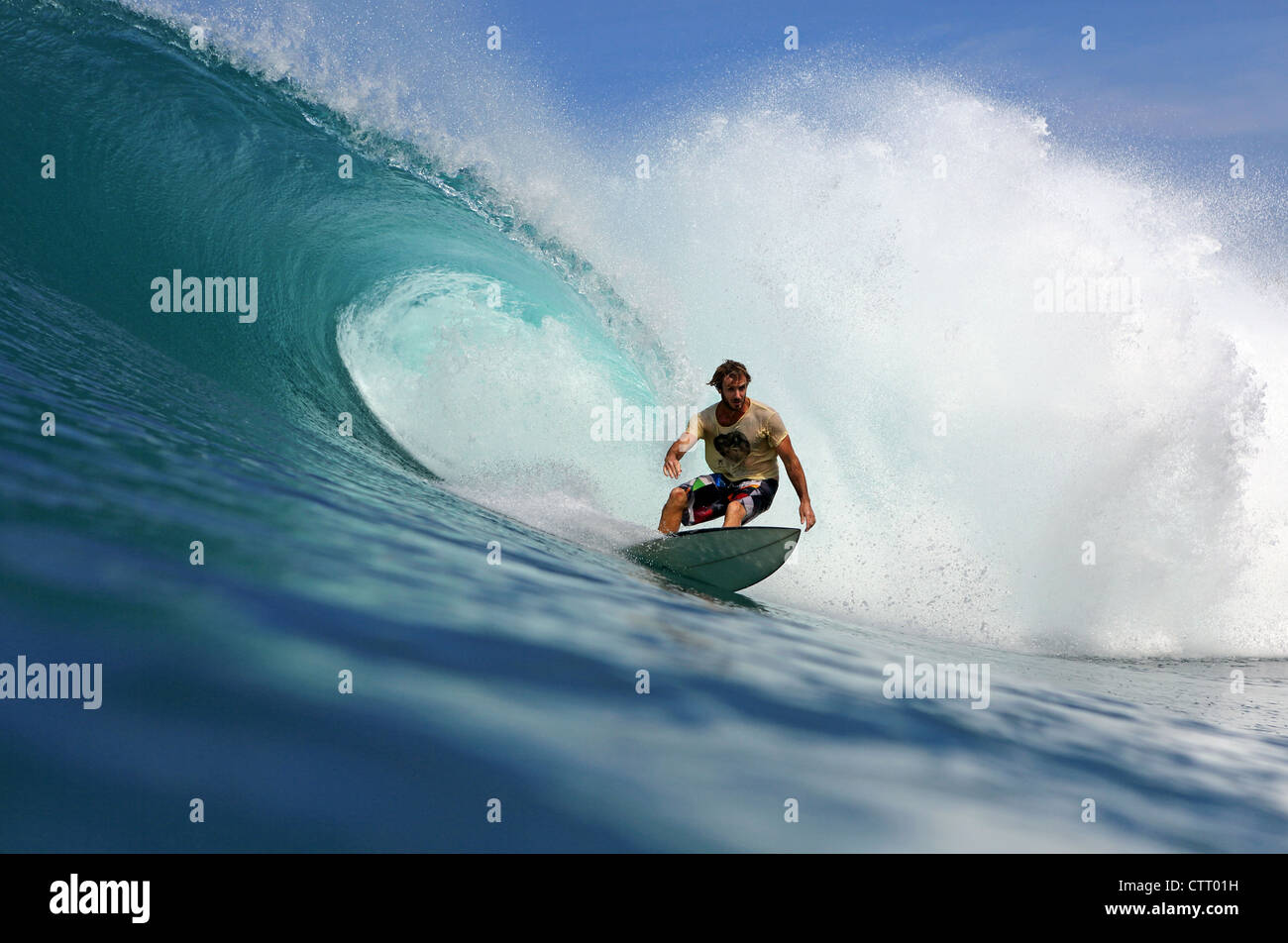 Surfista australiano in sella a una grande onda cava su un telecomando reef break sull'isola di Nias, Sumatra. Foto Stock