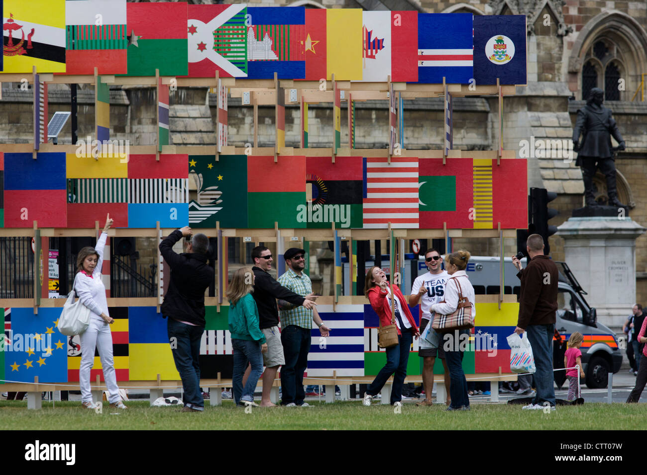 I visitatori di Londra per le Olimpiadi del 2012 ammirare la Casa delle bandiere' una struttura di 206 pannelli contenenti la bandiera le icone di tutti i paesi che partecipano a Londra nel 2012 Olimpiadi e Paraolimpiadi invernali. Progettato da architetti AY, la struttura si trova di fronte al Palazzo di Westminster in piazza del Parlamento. Sulla destra si trova la statua di Oliver Cromwell. Foto Stock