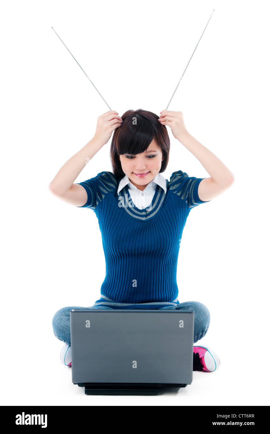 Attraente ragazza seduta sul pavimento con laptop e tenendo le antenne sulla testa Foto Stock