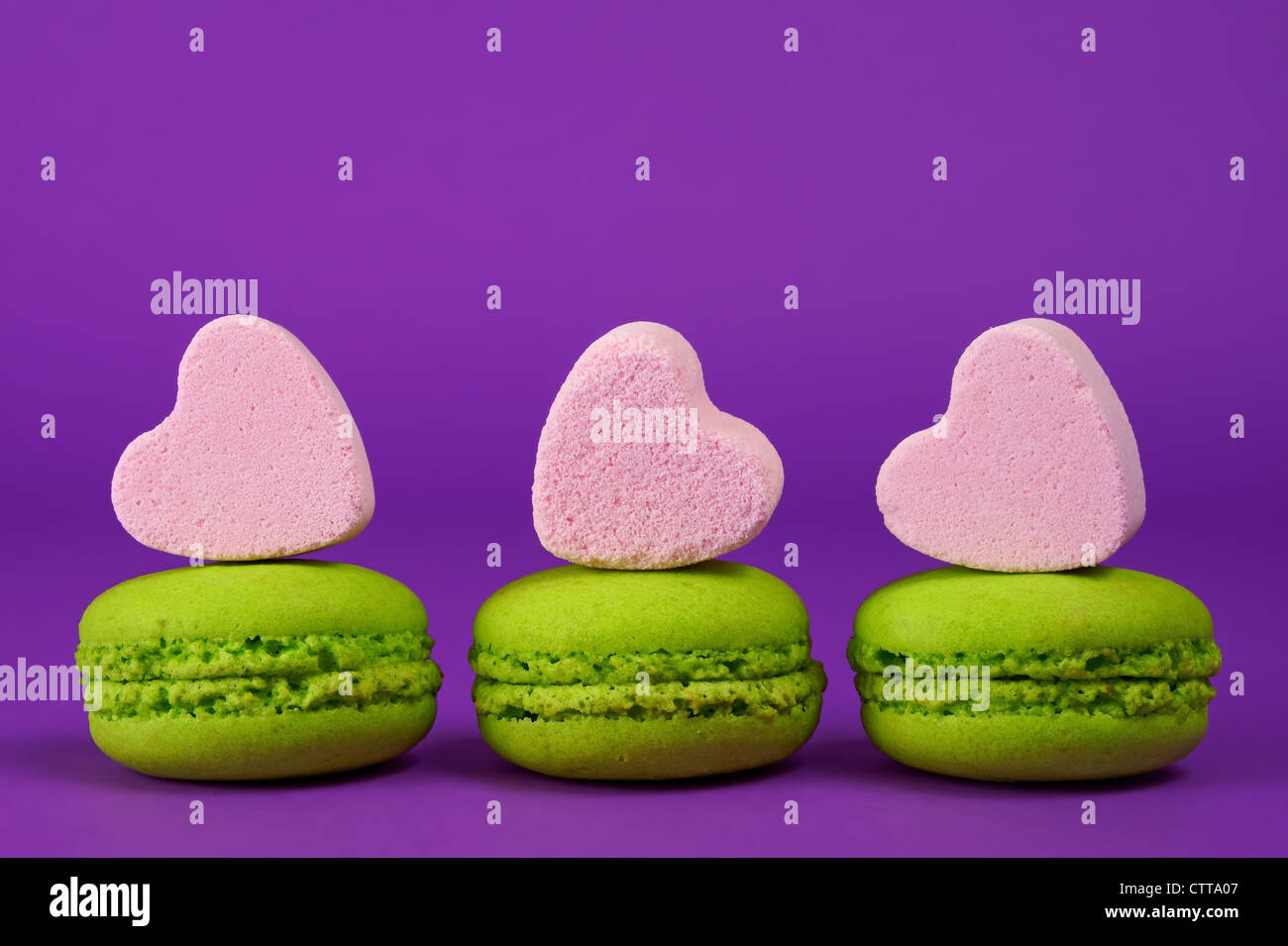 Il pistacchio amaretti e a forma di cuore di caramelle su uno sfondo viola Foto Stock