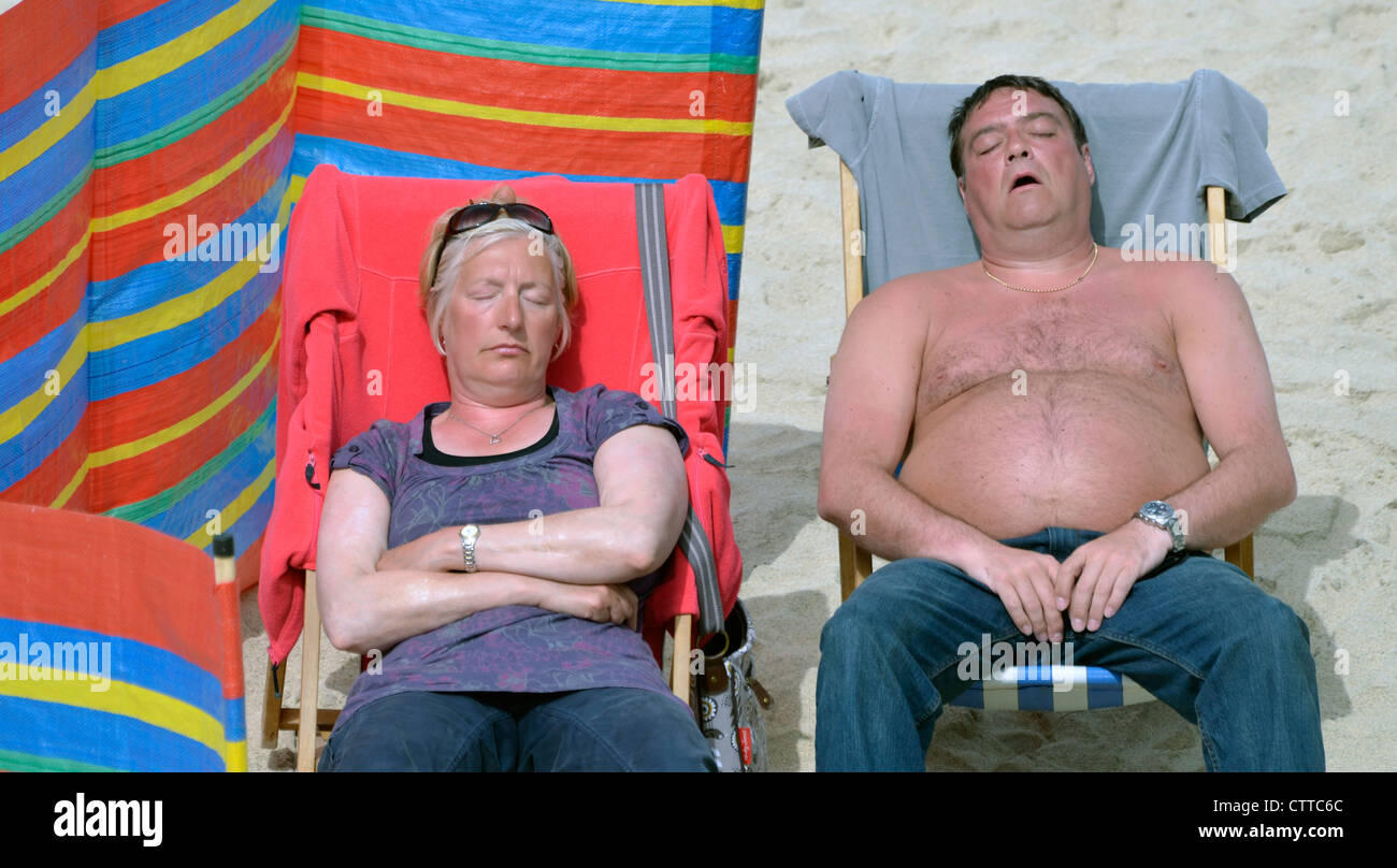 Uomo di mezza età e la donna addormentato in sedie a sdraio sulla spiaggia Sunny Beach Foto Stock