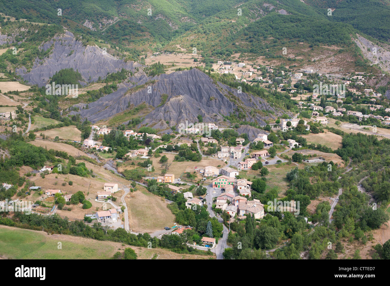 VISTA AEREA. Villaggio in un paesaggio naturale di terre di tasso composto di marl nero. La Robine-sur-Galabre, Alpes-de-Haute-Provence, Francia. Foto Stock