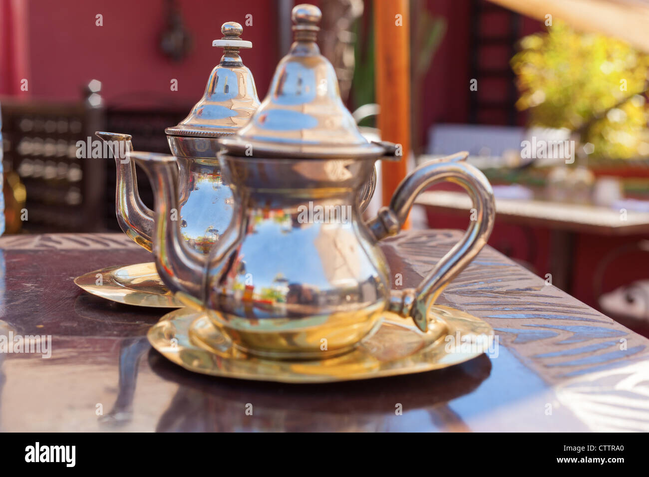 Due d'argento teiere immessi sul loro piastre essendo focalizzata più lontano in una di Marrakesh ristorante (Marocco) Foto Stock