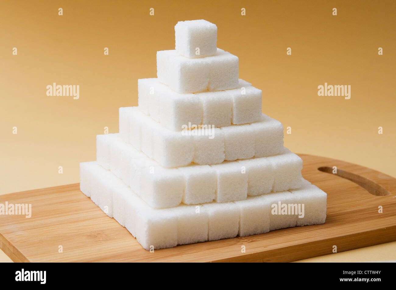 Zollette di zucchero piramide su un basckground giallo Foto stock - Alamy