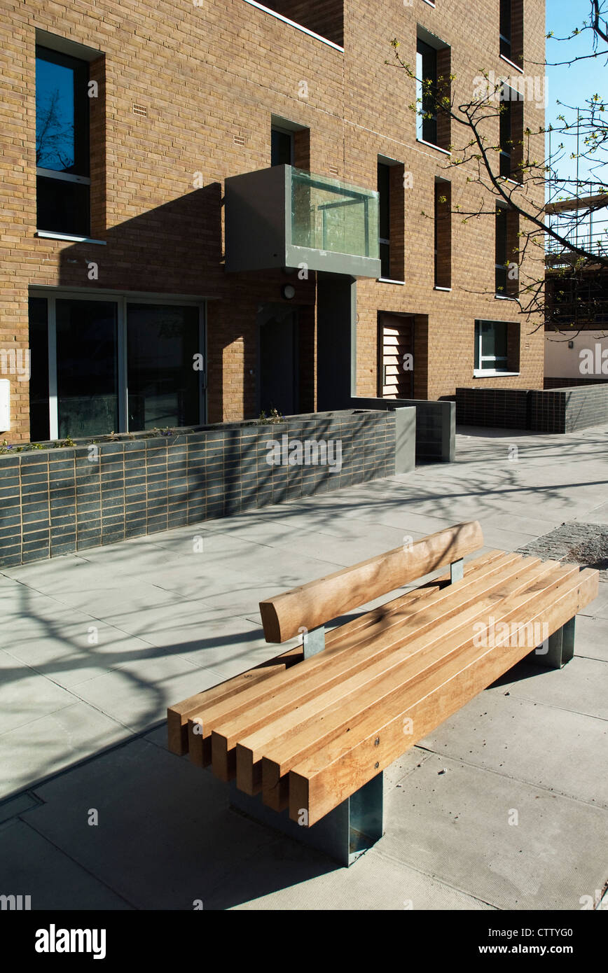 Panca in legno su un marciapiede al di fuori di un alloggiamento di sviluppo. Croce di prua, East London, Regno Unito. Foto Stock