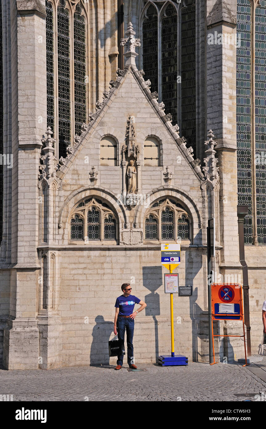 Leuven / Louvain, Belgio. St Pieterskerk / la chiesa di San Pietro (15thC tardo gotico). Uomo in piedi alla temporanea fermata del bus Foto Stock