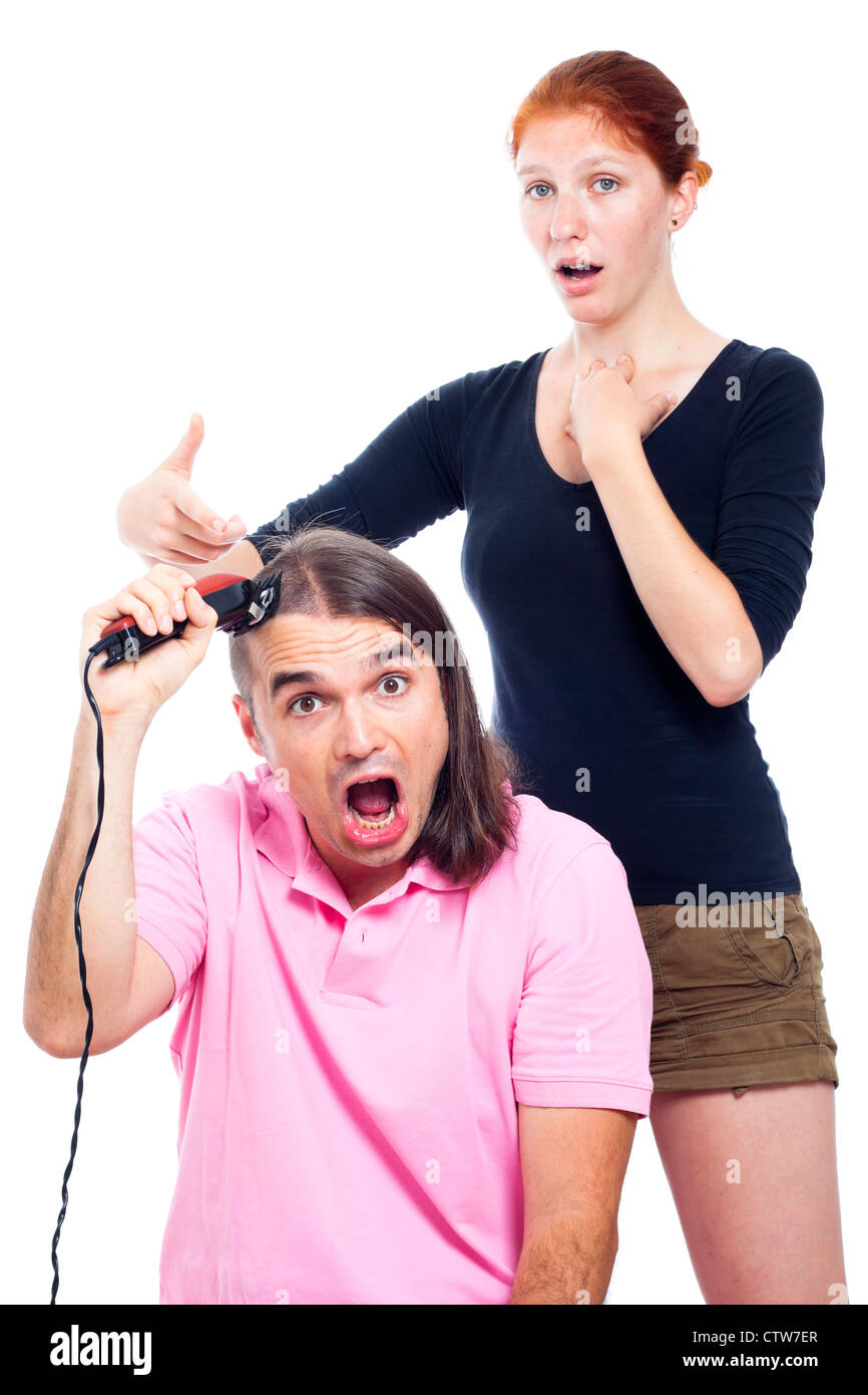 Sconvolto dai capelli lunghi uomo urlando, rasatura la sua testa con il rifinitore per i peli e la donna rivolta a lui, isolati su sfondo bianco. Foto Stock