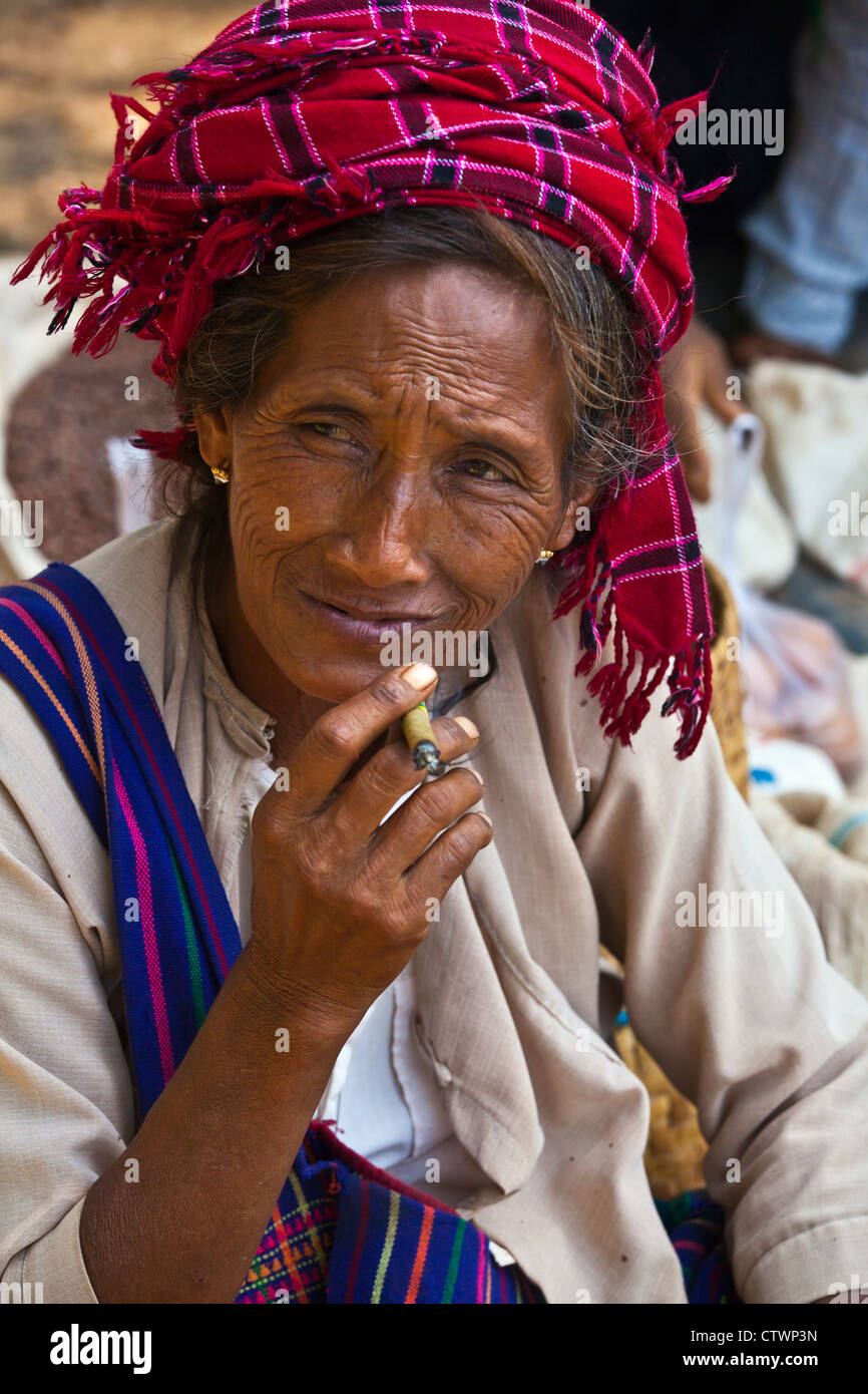 Una donna SHAN fuma un sigaro al mercato YWAMA sul modo di INDEIN - Lago Inle, MYANMAR Foto Stock