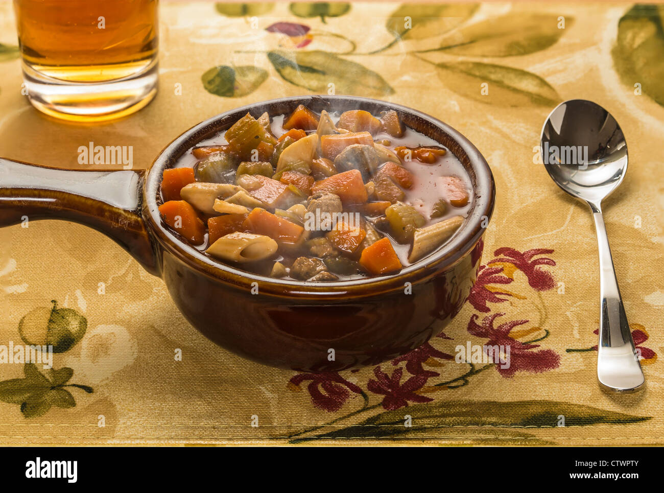 Recipiente di ceramica di polpetta italiana zuppa su tessuto di cartellone con cucchiaio e bicchiere di acqua Foto Stock