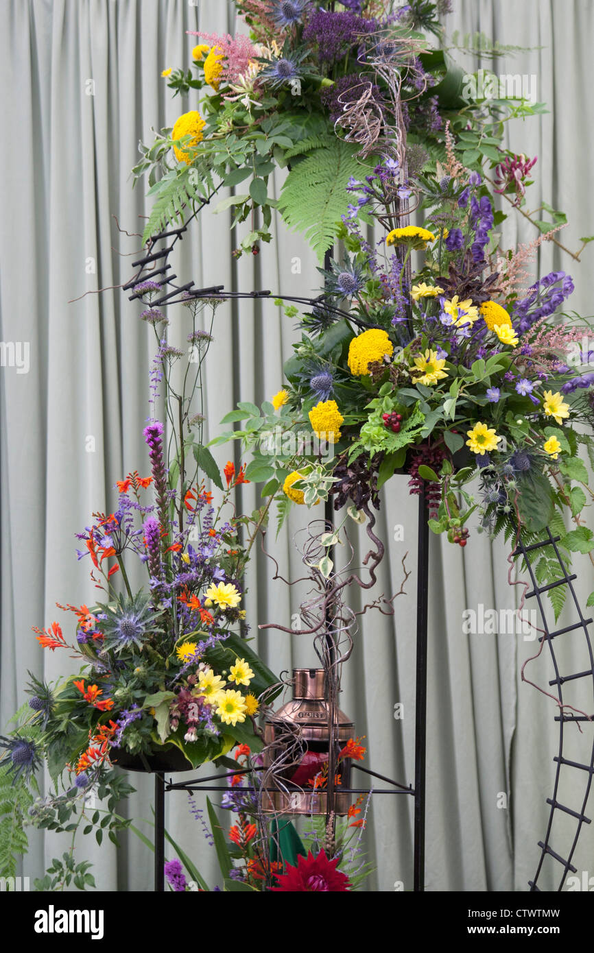 Un display floreali utilizzando eryngium,crocosmia,bacche,leycestra,crisantemi,agapanthus,succhiare miele e astilbe. Foto Stock