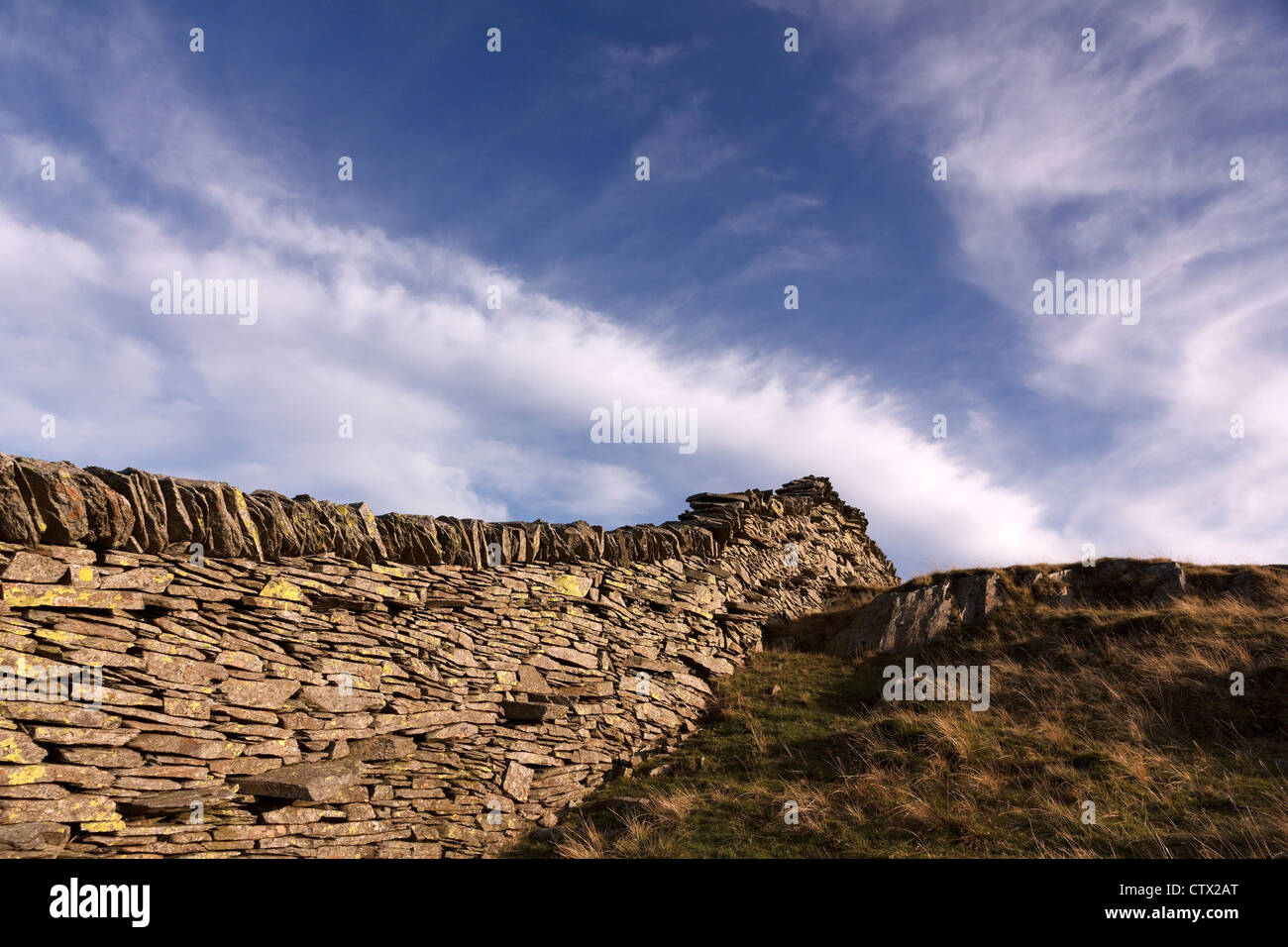 Il vecchio muro di pietra a secco in ardesia su Lingmoor cadde contro il cielo blu con le nuvole di Cirrus, Lake District, Cumbria, Inghilterra, Regno Unito Foto Stock