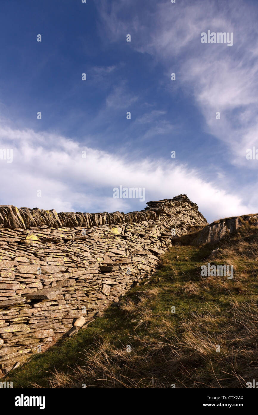 Il vecchio muro di pietra a secco in ardesia su Lingmoor cadde contro il cielo blu con le nuvole di Cirrus, Lake District, Cumbria, Inghilterra, Regno Unito Foto Stock