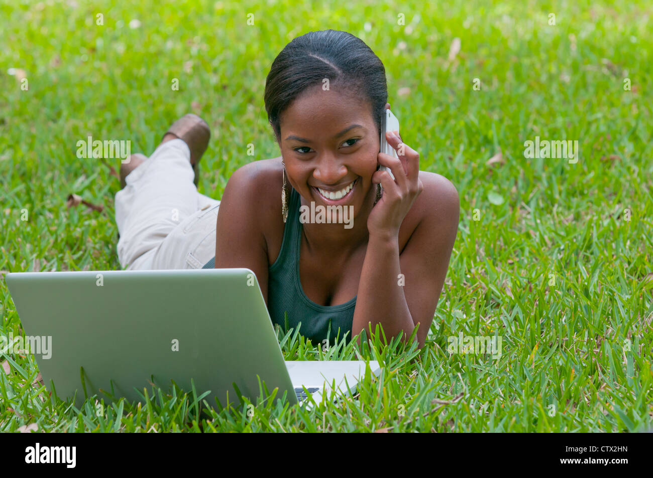 Giovane africano donna americana studente parlando al telefono cellulare all'aperto con un laptop Foto Stock