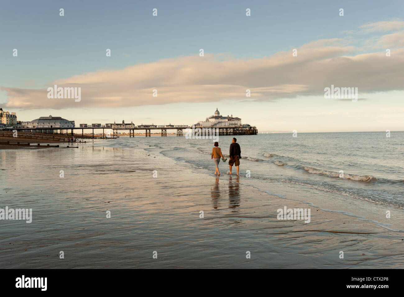 Due persone che camminano sulla sabbia a bassa marea a Eastbourne, East Sussex, Inghilterra. Foto Stock