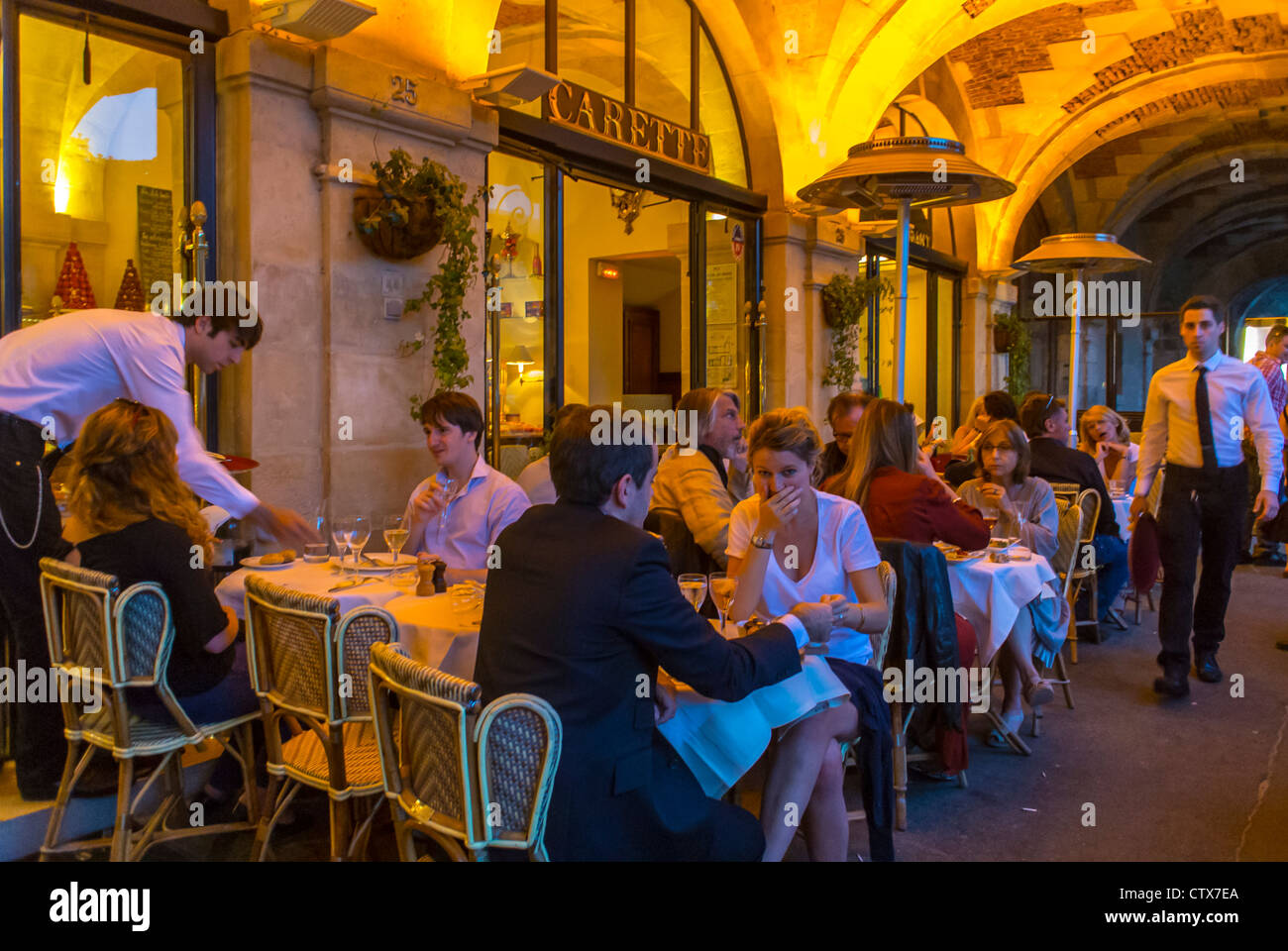 Parigi, Francia, People Sharing Meals, cena, al Bistro Francese, Ristorante Café, in Place des Vosges, nel quartiere Marais, alla notte 'Carette' in Terrazza donne pranzo terrasse, ristorante affollato, ristorante coppia Francia Foto Stock