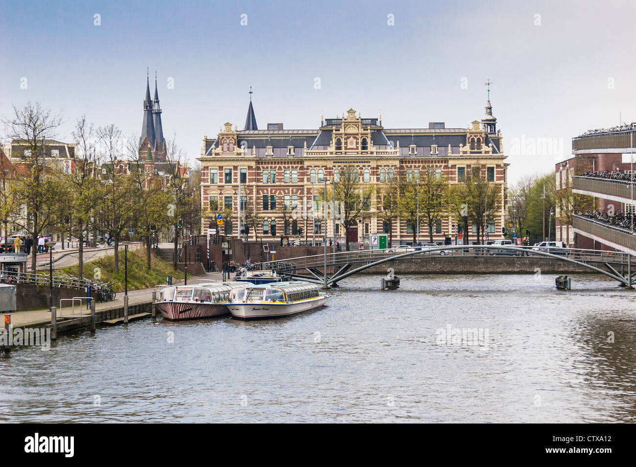I canali del porto della città di Amsterdam con la stazione ferroviaria centrale, il garage per biciclette e le gite turistiche sui canali, in Sud Olanda, Paesi Bassi. Foto Stock