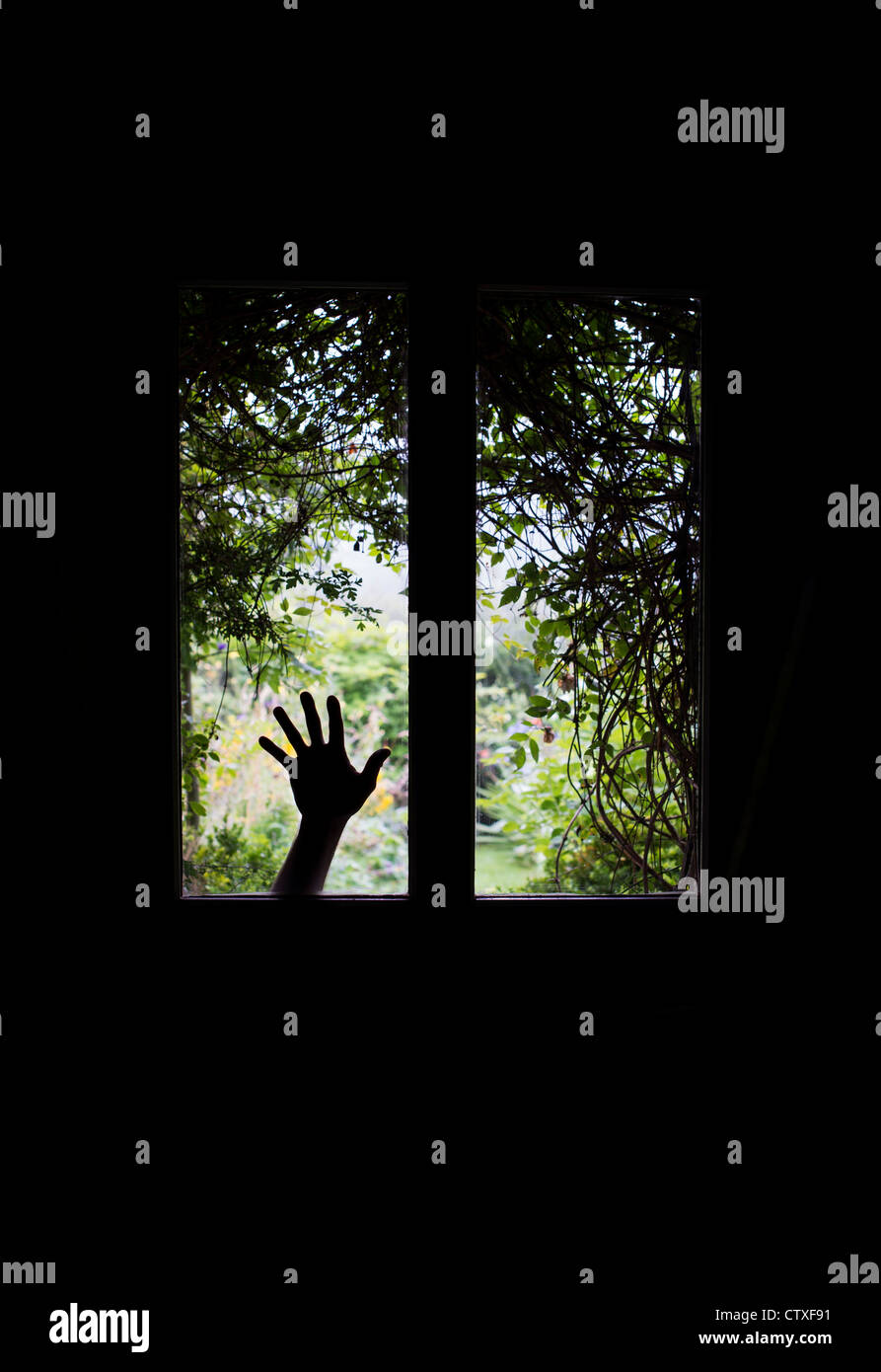 Silhouette a mano contro le finestre di vetro in una porta anteriore nella parte anteriore di una ricoperta con vista giardino. Regno Unito Foto Stock